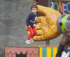 As fotos mostram as apresentações de várias modalidades do teatro de bonecos no Festival, com as crianças lotando as sessões e fazendo foto no boneco gigante e coloorido em frente ao Teatro Guaíra. 