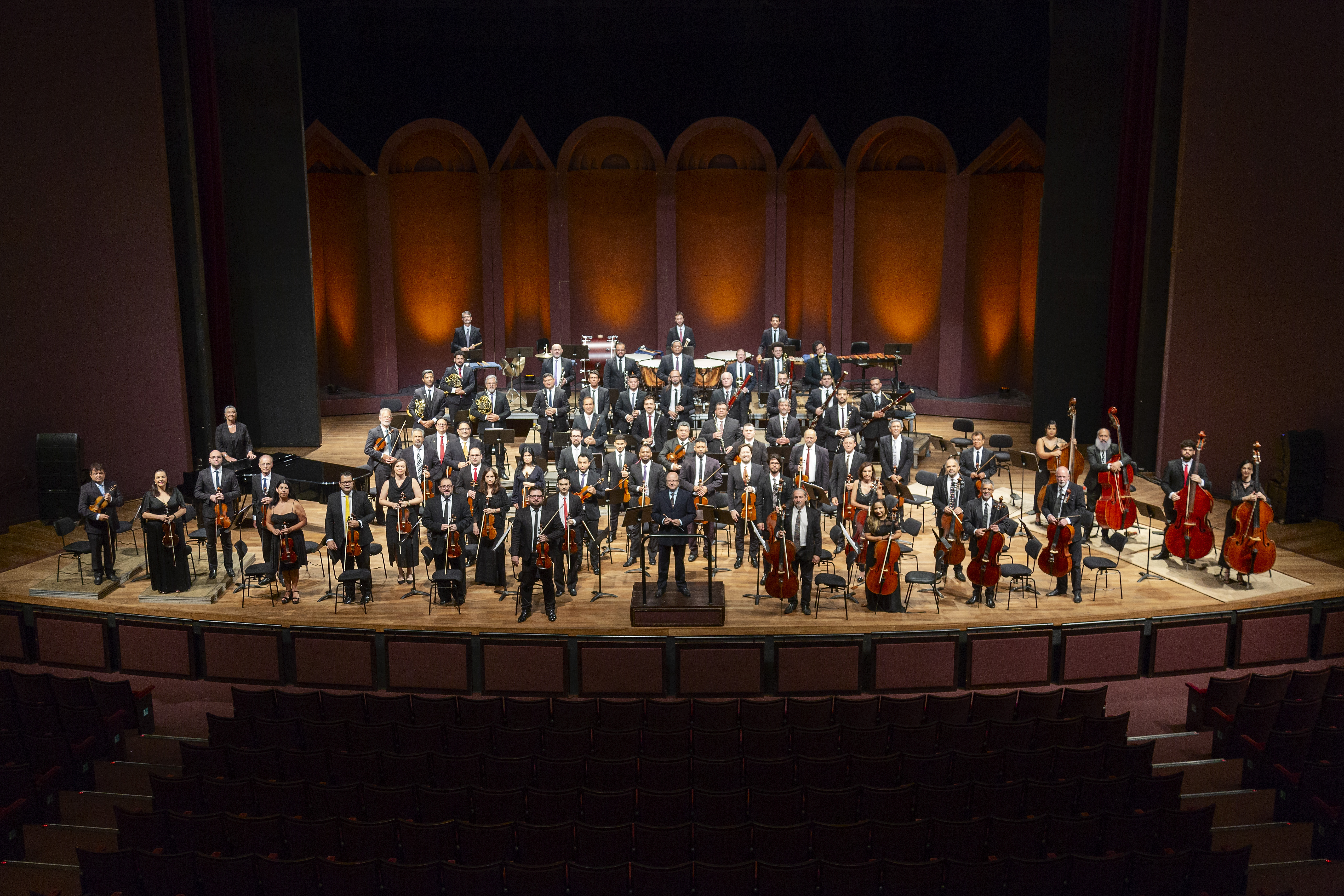 Orquestra Sinfônica do Paraná completa em posição no palco do Teatro Guaíra. No centro, o regente titular Roberto Tibiriçá.