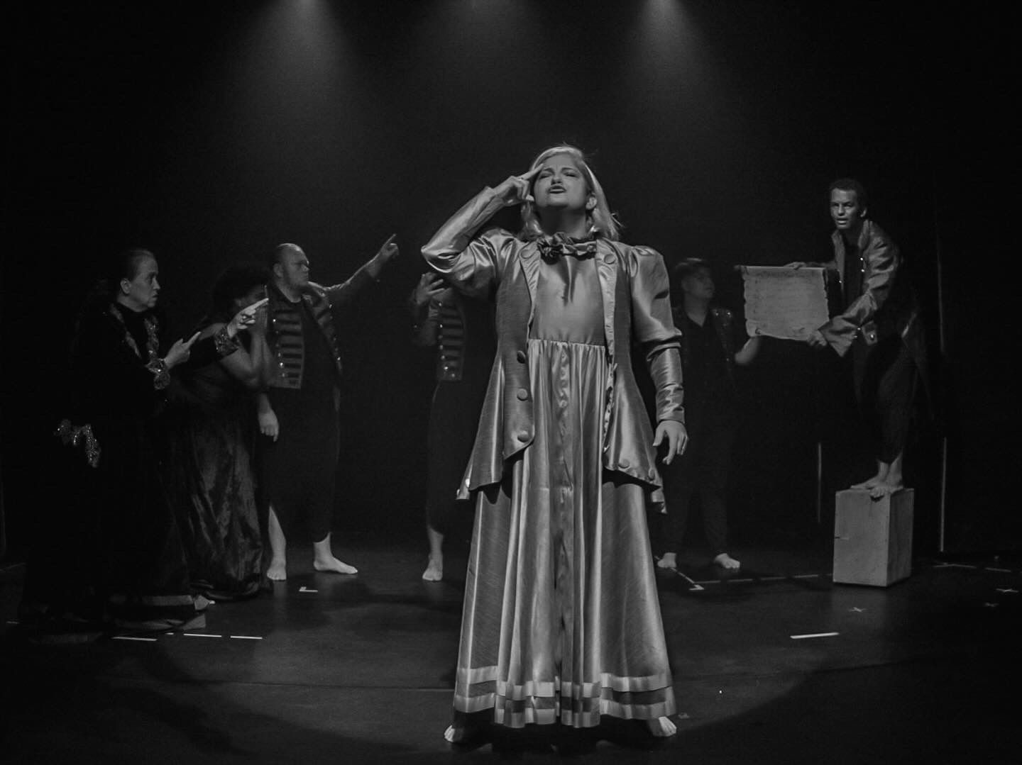 personagem com vestido a frente de outros atores. foto em preto e branco