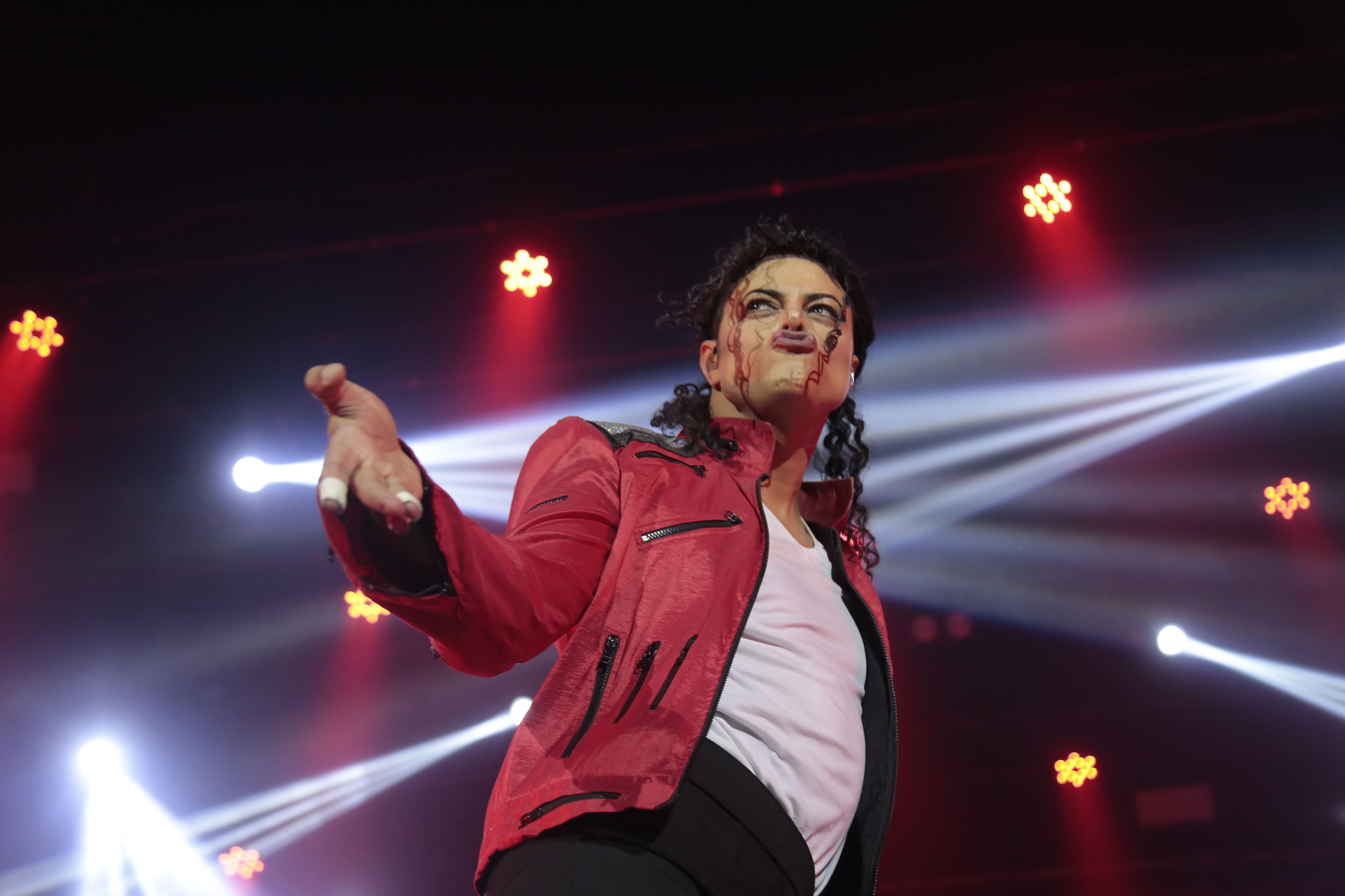 Rodrigo Teaser em show. Figurino vermelho e branco, luzes vermelhas ao fundo