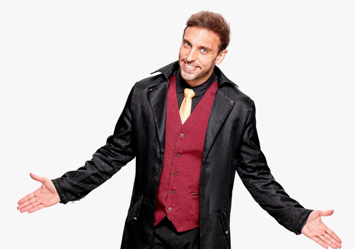 Léo Lins em frente a fundo branco com braços abertos e sorrindo