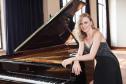 A pianista Olga Kopylova se debruça por sobre um piano de cauda