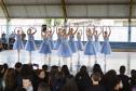 Grupo de dança se apresenta aos alunos no pátio da escola. As bailarinas vestem roupas na cor azul clara. 