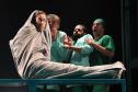 Cenas do espetáculo, com atores vestidos de médicos e uma paciente em cenário de sala de cirurgia