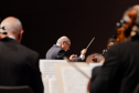maestro regendo orquestra, músicos de costas