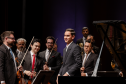 pianista sorrindo à frente de músicos da OSP