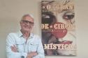 Gilberto Carbonar, funcionário mais antigo do Teatro Guaíra, em atividade há 49 anos, posando ao lado do cartaz de divulgação de “O Grande Circo Místico”