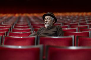 Douglas Rangel, sentado em meio às poltronas da plateia do Teatro Guaíra