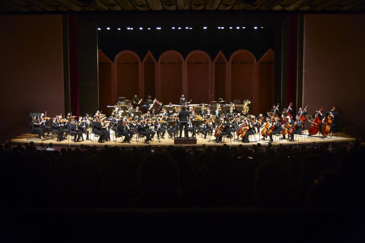 Foto dos músicos da OSP tocando seus instrumentos no palco do Guairão