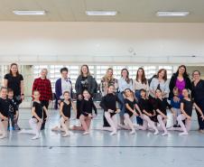 Mães e bailarinas e bailarinso da Escola se posicionam para registro. 