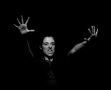 atriz em cena com mãos ao alto, foto em preto e branco