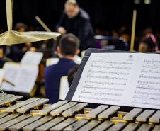 instrumentos e maestro aparecendo desfocado ao fundo