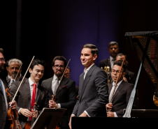 pianista sorrindo à frente de músicos da OSP