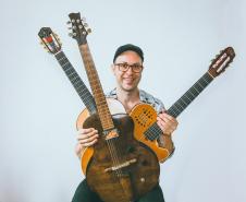 Músico Rodrigo Simões, com 3 instrumentos de corda