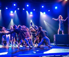 cena de Bombshell - iluminação azul e atores dançando em direção à personagem que representa Marilyn Monroe