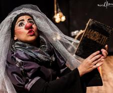 palhaça com tecido simulando um véu enquanto lê MACBETH