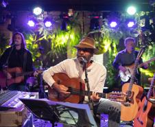 Almir Sater e banda com instrumentos e luzes ao fundo
