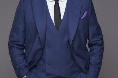 Retrato de Karnal com terno azul, camisa branca e gravata preta.