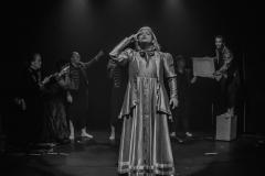 personagem com vestido a frente de outros atores. foto em preto e branco