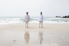 Arnaldo Antunes e Vitor Araújo com roupas claras na beira do mar 