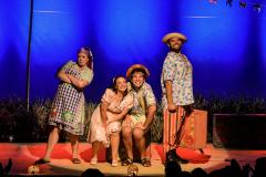 Personagens do musical posando para foto em frente ao cenário