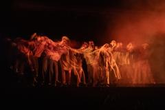 personagens em peça "Uma jornada no sertão", com luzes vermelhas e cenário típico regional 