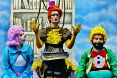 Personagens Ritinha, Doroteia e Nico em frente a uma prateleira da biblioteca