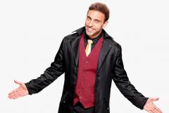 Léo Lins em frente a fundo branco com braços abertos e sorrindo