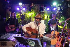 Almir Sater e banda com instrumentos e luzes ao fundo