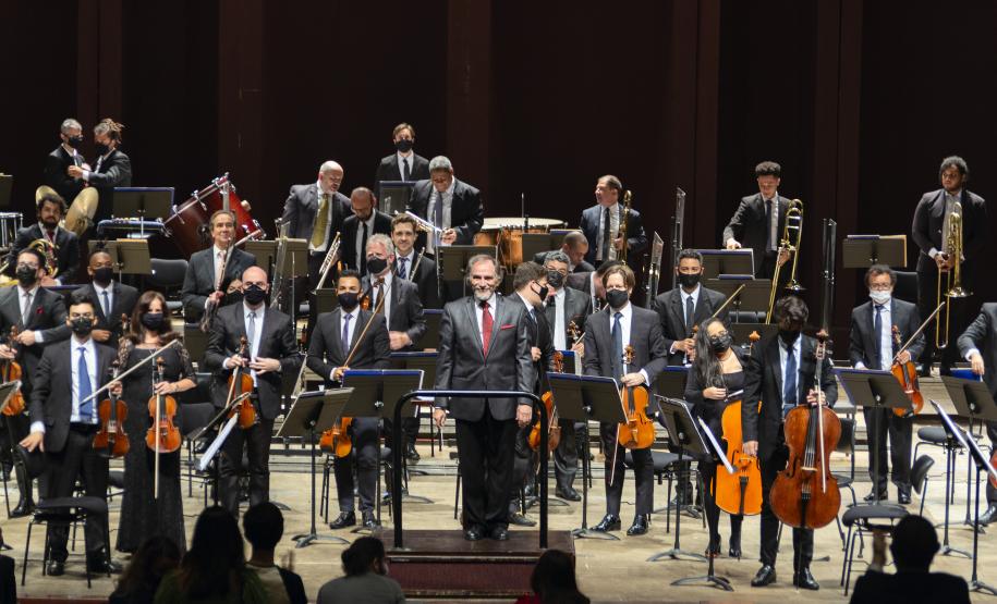 Músicos em pé no palco, agradecendo aplausos
