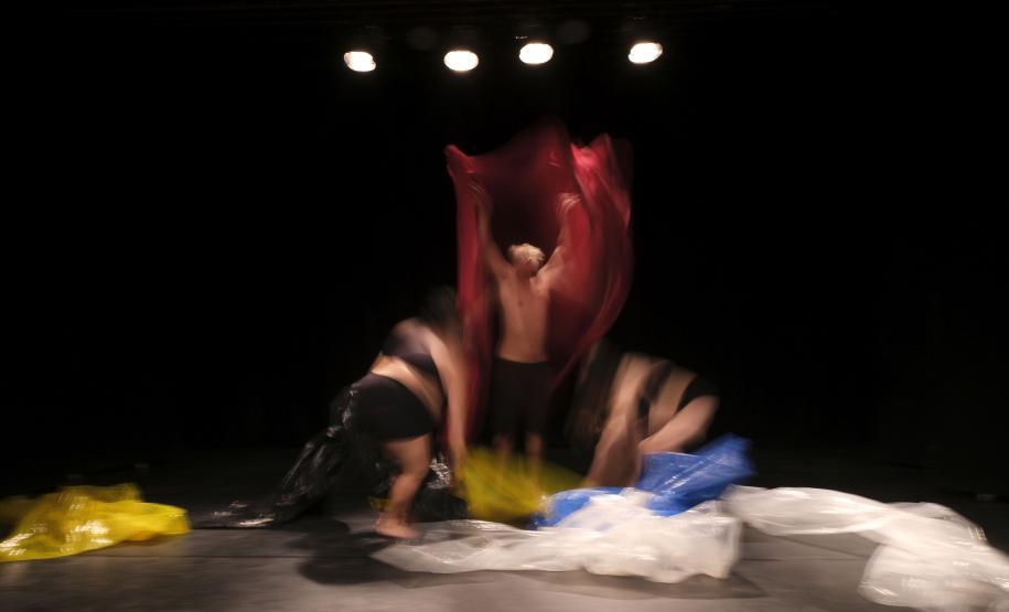 As fotos mostram parte das cenas criandas, com três atores e material plástico sendo enrolado nos corpos deles.