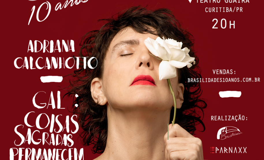 Adriana Calcanhoto aparece com uma rosa vermelha ao lado e, depois, na frente do rosto. No fundo, a cor vermelha também.