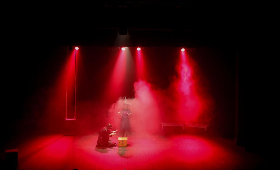 personagens em cena com iluminação vermelha e fumaça