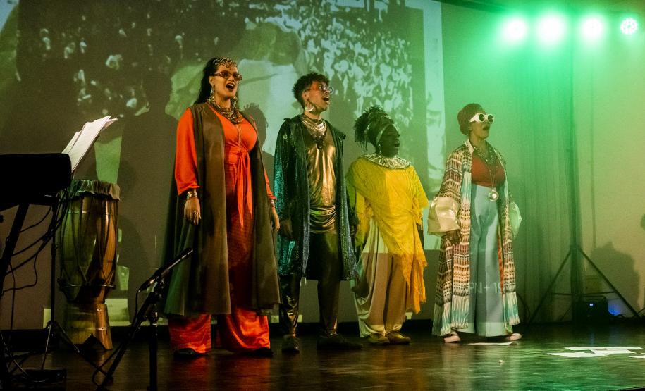 Elenco da ópera em cena com iluminação colorida