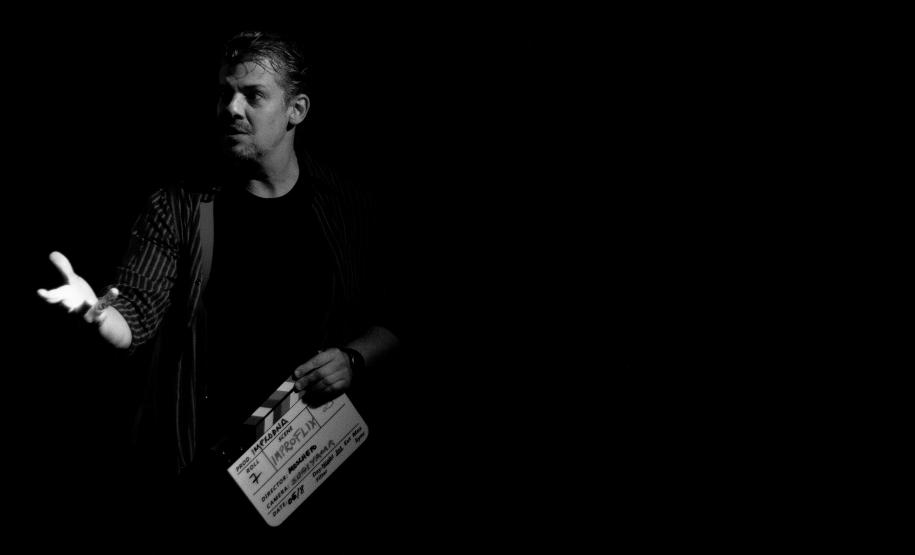 diretor em cena segurando claquete, foto em preto e branco