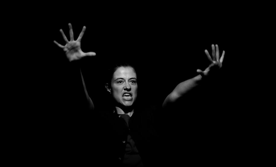 atriz em cena com mãos ao alto, foto em preto e branco