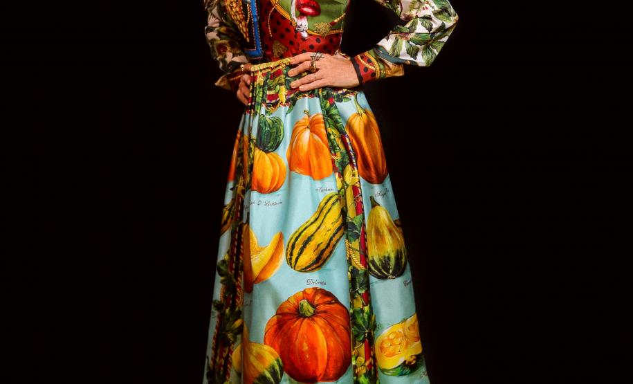 elba posando para foto com vestido colorido em um fundo preto