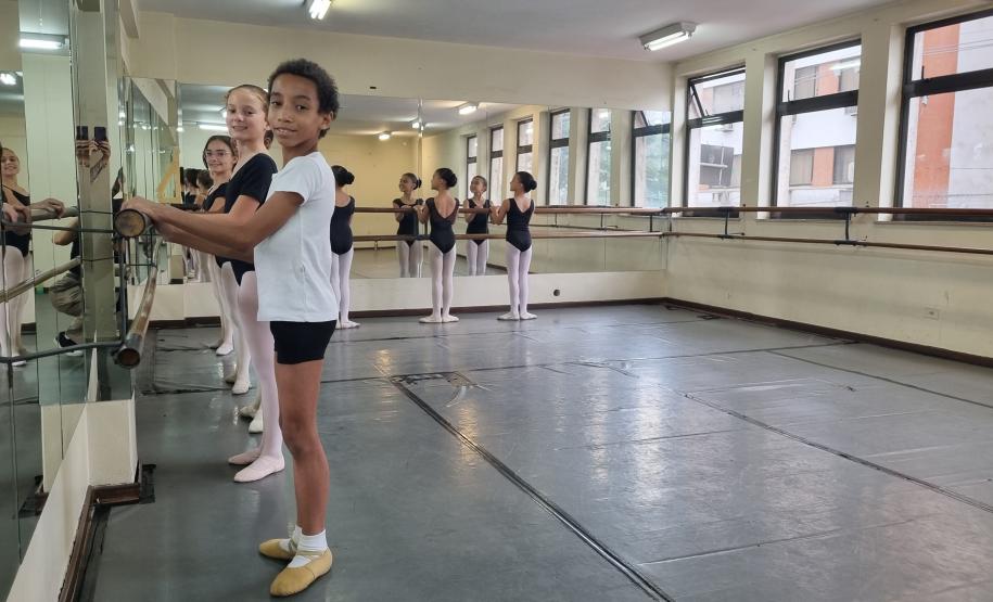 José, 11 anos posicionado em frente ao espelho. outras alunas estão na mesma posição atrás do bailarino