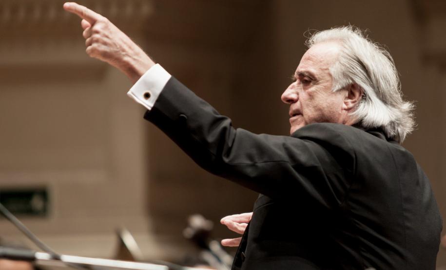 maestro, de terno preto, regendo orquestra