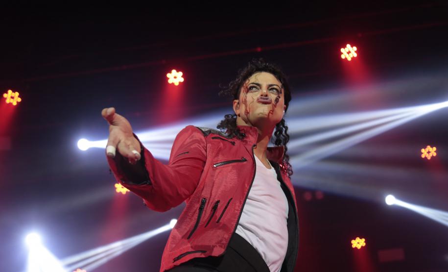 Rodrigo Teaser em show. Figurino vermelho e branco, luzes vermelhas ao fundo