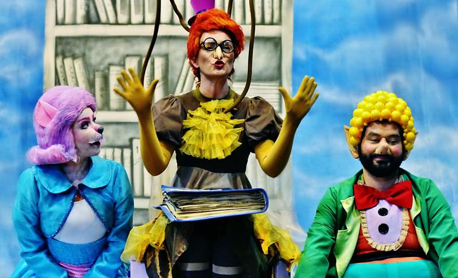 Personagens Ritinha, Doroteia e Nico em frente a uma prateleira da biblioteca