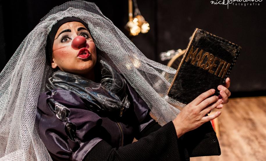 palhaça com tecido simulando um véu enquanto lê MACBETH