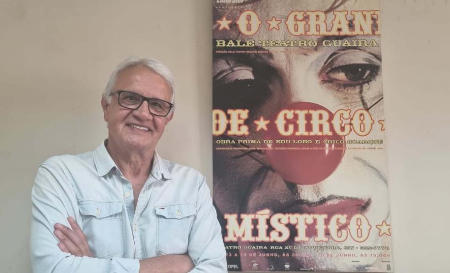 Gilberto Carbonar, funcionário mais antigo do Teatro Guaíra, em atividade há 49 anos, posando ao lado do cartaz de divulgação de “O Grande Circo Místico”
